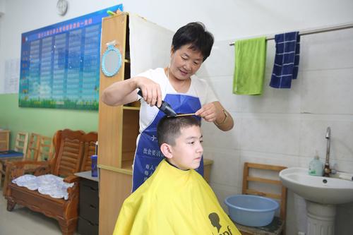 图五：十二师中学宿管老师常林给学生理发